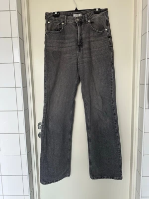 Grå raka jeans från Pull&Bear EU 38 - Snygga grå jeans från Pull&Bear med rak passform och klassisk femficksdesign. Jeansen har hög midja och är tillverkade i denim med en lätt tvättad look. Perfekta för en avslappnad och trendig stil.