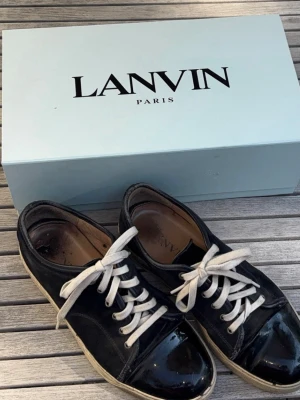 Mörk blåa Lanvin sneakers med lackdetaljer - Snygga mörkblåa mocka sneakers från Lanvin med vita skosnören och en gummi toe cap. Storlek 43 men passar också storlek 44. Låda kommer med. Priset ej satt i sten, tar gärna emot bud