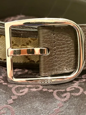 Gucci: Vackert 100 % äkta autentiserat skinnbälte män - Ett vackert herrbälte från Gucci med blankt silverfärgat spänne. Bältet bär Guccis klassiska monogrammönster. Mycket gott vintageskick. Storlek herr L / 100 cm. Autentiserat 100 % äkta. Även äkta skinn.