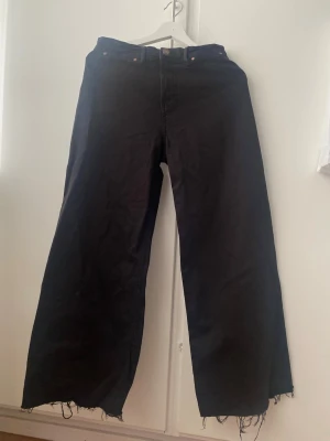 Svarta wide leg jeans Stradivarius - Svarta jeans från Stradivarius i modell wide leg med råa, fransiga benslut. Klassisk femficksdesign och hög midja. Perfekta för en avslappnad och trendig look. Tillverkade i bomullsmix för skön känsla. Short 