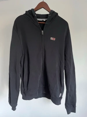 Napapijri zip hoodie - Napapijri zip hoodie Storlek: L Passform: Regular Fit Krage: Huvtröja med dragkedja och justerbar huva Material: Bomull Mått: Bröstvidd 108 cm, längd 62 cm, axel 48 cm Skick: Huvtröjan är i ett väldigt fint skick utan defekter  Nypris cirka: 1 000 kr