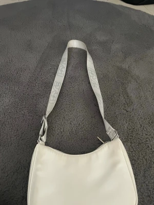 Vit axelväska - Säljer denna jätte snygga axelväska från H&M!  Dom man ser på sista bilen så är bandet lite färgat..🩵