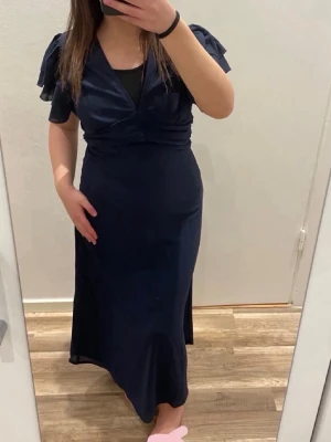 Elegant mörkblå klänning – helt ny (XS, Bubbleroom) - Säljer en elegant och stilren klänning i mörkblått 💙 Den har en smickrande passform som markerar midjan och faller fint längs kroppen, vilket ger ett klassiskt och sofistikerat intryck. Passar perfekt till fest, middag eller andra tillfällen där du vill känna dig extra fin.  ✨ Aldrig använd – helt ny ✨ Bekvämt material med fint fall ✨ Tidlös modell som passar många tillfällen  Säljer den då den tyvärr inte kommit till använd. Hör gärna av dig vid frågor 💌