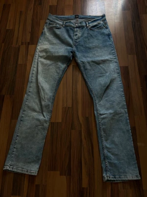 Ljusblå raka jeans montén - Säljer ett par ljusblå jeans med rak passform och klassisk femficksdesign. Jeansen har normal midja och är tillverkade i denim med en lätt tvättad look. Perfekta för en avslappnad och stilren outfit. Mindre i storleken har även ett par gråa till försäljning 
