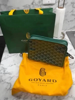 Grön handväska med mönster - Snygg grön handväska från  med klassiskt grafiskt mönster i vitt och grått. Väskan har dragkedja och detaljer i grönt läder. Kommer med original dustbag och shoppingpåse. Perfekt för dig som gillar exklusiva accessoarer.