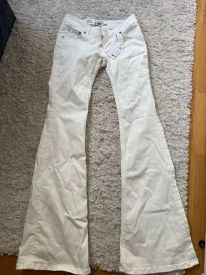 Vita utsvängda jeans med låg midja - Säljer ett par vita jeans med låg midja och riktigt utsvängda ben från lager 157. De är aldrig använda bara testade.