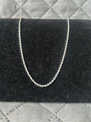 Tunt tvinnat silverfärgat halsband - Säljer ett stilrent halsband i silverfärg med tvinnad kedja. Halsbandet har en enkel karbinhake och glänsande yta som ger en modern look. Perfekt för att lyfta vilken outfit som helst med en diskret touch av elegans. 45 cm. Checka in min profil för passande armband.