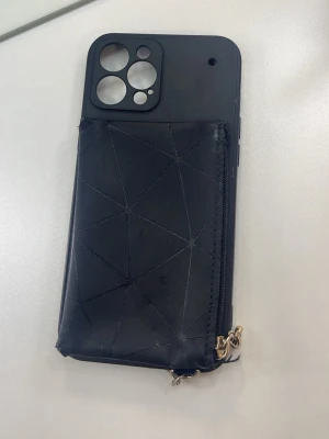  mobilskal 12 PRO MAX - Snyggt svart mobilskal med geometriskt mönster och praktisk dragkedjeficka på baksidan. Perfekt för att förvara kort eller övriga saker. Utrustad med metallring för enkel upphängning eller nyckelring. Mobilskalet är till iPhone 12 PRO MAX 