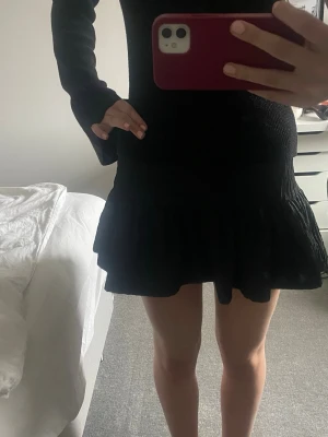 Svart volangkjol med resårmidja - Säljer en svart kjol med volangkant och resår i midjan. Kjolen har en kort och flowy passform som ger en snygg siluett. Perfekt att matcha med en stickad tröja eller crop top för en trendig look. Andvänd 2 gånger, den säljs inte längre från Zara!