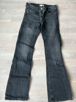 Svarta bootcut jeans  - Snygga svarta bootcut jeans och klassiska fem fickor. Jeansen har låg midja och utsvängda ben, perfekt för en avslappnad och trendig look. Materialet är denim med en skön känsla.