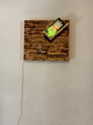 Jägermeister lampa  - Fin detalj att ha på väggen. Lampan är gjord av trä och ja en lampa bränt Jägermeister o lackat den. Mycket fin funkar som ja typ lampa men inte jätte starkt ljus kan byta pris 