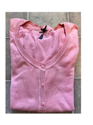 Rosa kofta med knappar och fickor - Söt rosa kofta med rund halsringning, knäppning framtill och två små fickor. Långärmad modell i mjukt, tunt stickat material. Perfekt att slänga över en topp för en chill look.