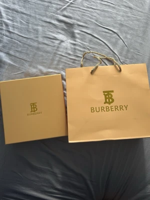 Beige shoppingväska  - Snygg shoppingväska i beige papper med guldiga detaljer och tvinnade handtag. Kommer med original ask och dustbag i matchande färg. Perfekt för dig som gillar lyxiga accessoarer och vill ha något extra till din shoppingrunda.