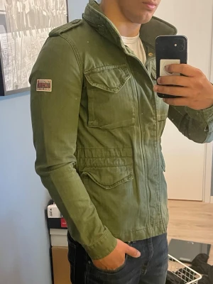 Superdry field jacket  - Säljer en otroligt fet field jacket från Superdry | Storlek small, jag är 179cm lång och 75kg. Den är tight på mig så bättre om du väger mindre än mig | Skick: 10/10, den är som ny, har ingen defekt osv utan riktigt fet och fräsch vårjacka. Kom gärna med prisförslag så kommer vi överäns om något 