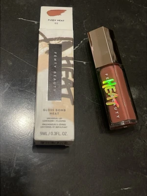 Fenty Beauty Gloss Bomb Heat Fussy - Fenty Beauty Gloss Bomb Heat i nyansen Fussy Heat 02. Ett läppglans med plumping-effekt i en varm, rosabrun ton. Kommer i en snygg, fyrkantig förpackning med spegelblankt lock och holografisk text. Innehåller 9 ml.