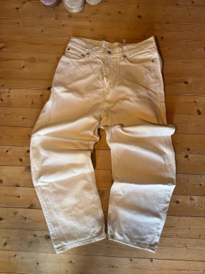 Vita jeans - Säljer ett par vita jeans från Weekday, modell Galaxy. Jeansen har rak passform, fem fickor och klassisk knappgylf. Tillverkade i 100% bomull för en skön och avslappnad känsla. Perfekta till en clean och stilren look.