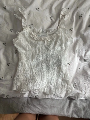 Vit spetslinnetopp från Pull&Bear - Supersöt vit linnetopp från Pull&Bear med volangdetaljer och breda axelband.