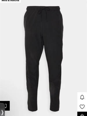 Svarta mjukisbyxor från Nike - Säljer ett par svarta mjukisbyxor från Nike med dragsko i midjan och diskret Nike-logga på benet. Byxorna har dragkedjeförsedda fickor och är tillverkade i ett mjukt, stretchigt material som ger en clean och sportig look. Nypris: 879kr 