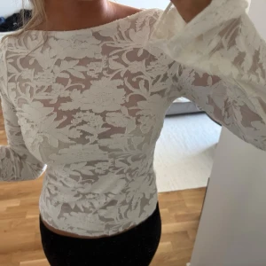Vit spetsblus med blommönster - Säljer en vit, långärmad blus i spets med blommigt mönster. Blusen har lätt utsvängda ärmslut och är något transparent. Endast testad, prislapp kvar💞