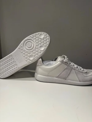 Vita Maison Margiela gats - Säljer ett par helvita Maison Margiela gats. Klassisk låg modell med vita skosnören och unik sula med präglat mönster. Skorna är helt nya och är i storlek 43 men passar även 42. 