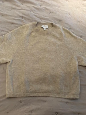 Beige stickad tröja & Other Stories - Mysig beige stickad tröja från & Other Stories med rund halsringning och ribbade muddar. Tröjan har en avslappnad passform och är tillverkad i mjukt material som passar perfekt för lager på lager. Enkel och stilren design som funkar till allt.