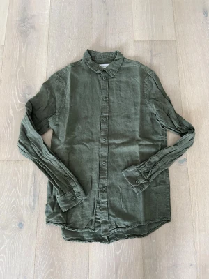Linneskjorta från Pier One - Snygg grön skjorta från Pier One i mjukt linne. Skjortan har klassisk krage, långa ärmar och knappar hela vägen framtill. Perfekt till jeans eller chinos för en avslappnad men stilren look.