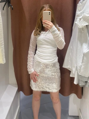 Vit paljettkjol - Säljer en kort vit kjol täckt med glittriga paljetter och en lätt volangkant nedtill. Kjolen har en rak passform och ger en riktigt snygg och trendig look. Perfekt för dig som vill sticka ut lite extra.🤍🪩 Den är köpt sommaren 2023 (augusti) från Bikbok. Säljer då den är för liten☹️ Några paljetter har fallit bort men inget man tänker på. Paljetterna är stora 