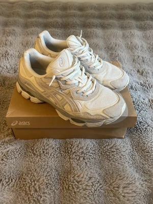 Asics gel nyc cream white  - Säljer ett par fräscha vita Asics sneakers med cool mesh och mockadetaljer. Skorna har chunky sula och klassisk Asics-logga på sidan. Perfekta för dig som gillar sportig och trendig stil. Sköna att gå i och passar till det mesta.