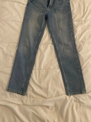 Ljusblå raka jeans från Gina Tricot.  - Säljer ett par ljusblå jeans från Gina Tricot med rak passform och klassisk femficksdesign. Jeansen har dragkedjegylf och knapp, samt subtila slitningar för en avslappnad look. Perfekta till en casual outfit.