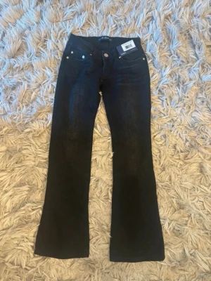 svarta  bootcut jeans från G.Rise - Snygga svarta jeans från G.Rise med bootcut passform och klassisk femficksdesign. Jeansen har gylf med knapp och dragkedja samt bälteshällor. Perfekta för dig som gillar en tidlös och trendig look.