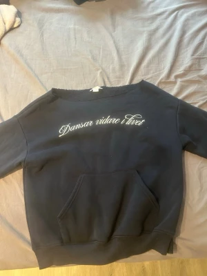 Marinblå hoodie Gina Tricot med tryck - Marinblå hoodie från Gina Tricot med vit text 'Dansar vidare i livet' på bröstet. Tröjan har en stor magficka och ribbade muddar. Materialet är mjukt och bekvämt, perfekt för chill dagar. Rund halsringning utan huva.