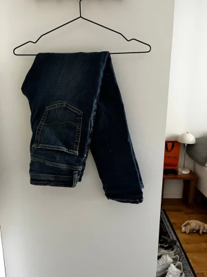 Mörkblå raka jeans - Säljer ett par mörkblå jeans med slim passform och klassiska bakfickor. Jeansen har en tidlös look och passar perfekt till en avslappnad stil. Materialet är denim och färgen är djupblå. Perfekta för dig som gillar enkel och snygg design.