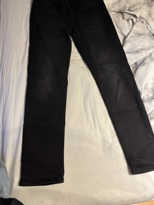 Svarta  jeans - Säljer ett par svarta jack & jones jeans med klassisk femficksdesign. Jeansen har raka ben och är tillverkade i ett stretchigt material som ger en bekväm passform. Perfekta för dig som gillar en stilren och enkel look.