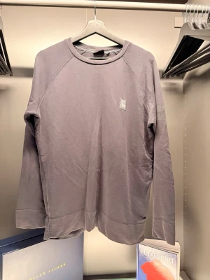 Sailracing - En stilren svart långärmad tröja med rund halsringning och diskret logotyp på bröstet. Tröjan är i mjuk bomull och har en avslappnad passform, perfekt för en chill vardagslook.