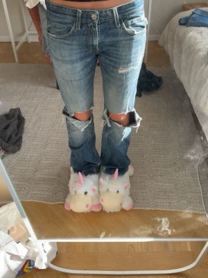 Blå slitna bootcut jeans från Replay - Säljer ett par blå bootcut jeans från Replay med slitningar och stora hål vid knäna. Jeansen har klassisk femficksdesign, låg midja och är tillverkade i denim. Perfekta för en avslappnad och trendig look, midjemått 38cm och innerbenslängd 78cm 💓💓