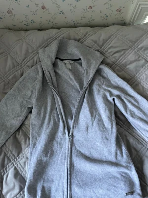 Ljusgrå hoodie med dragkedja - Säljer en ljusgrå hoodie från H&M med dragkedja framtill och huva. Hoodien är tillverkad i mjukt bomullsmaterial och har en enkel, stilren design utan tryck eller mönster. Perfekt för en avslappnad och bekväm stil. Och en perfekt zip hoodie att ta på sig när det blir lite kyligt.