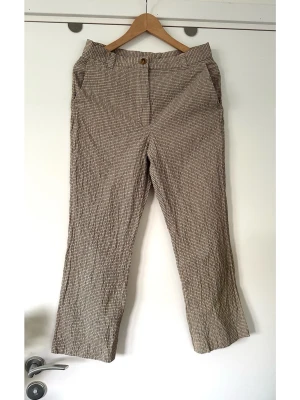 ARKET - Beige, gul, grå rutiga byxor - storlek 40 - Snygga beige / flerfärgade byxor från ARKET med små rutmönster i svart/grått, gult/beige och vitt. Storlek 40. Tidlös modell med raka ben, hög midja och bälteshällor. Stängs med knapp och dragkedja framtill samt har sidofickor. Härligt ”krinklat” tyg i 99% bomull och 1% elastan, så bra material som andas men ändå har lite lätt stretch för bästa passform. Perfekta för en stilren och trendig look. Mycket gott skick, som nya!