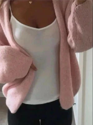 Ljusrosa fluffig kofta - Mysig ljusrosa kofta med öppen front och vida ärmar. Koftan är fluffig och har en avslappnad passform, perfekt att slänga över en topp. Passar dig som gillar en soft och trendig stil.