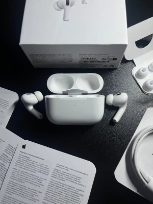Apple AirPods Pro 2 - Komplett - Säljer ett par vita Apple AirPods Pro 2 med laddningsetui. De är trådlösa in-ear-hörlurar med silikontoppar och aktiv brusreducering. Kommer med originalförpackning, extra öronproppar och laddningskabel. Perfekta för musik, samtal och träning.