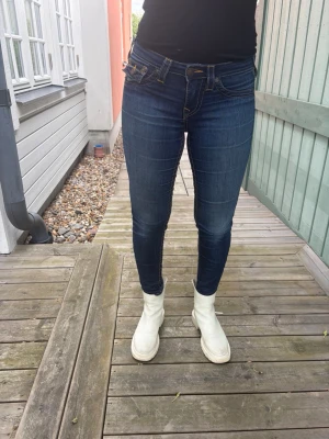Mörkblå Jeans True Religion - Säljer ett par mörkblå lågmidjade jeans från True Religion. Jeansen har låg midja och smal passform hela vägen ner. Materialet är stretchigt denim som sitter snyggt och bekvämt.