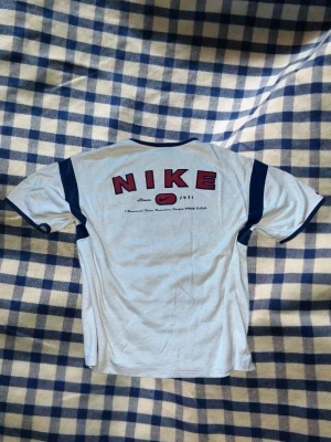 Vintage Nike t-shirt Y2K🏀🤍 - Säljer denna snygga vintage Nike t-shirt i vit med marinblå detaljer och stort Nike-tryck baktill. Perfekt Y2K/sportig stil och superfin till både vardag och streetwear.