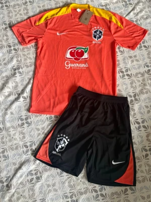 Brasilien träningsset Nike röd/gul - Brasil fotbollsset i storlek M. Shortsen har fickor med dragkedjor. Helt nya och oanvända, perfekt till sommaren. Hör gärna av vid frågor!
