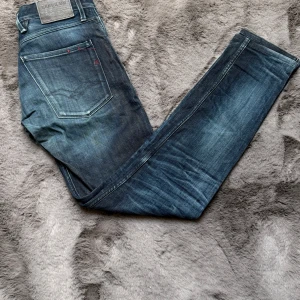 Blå raka jeans från Replay - Säljer ett par klassiska blå jeans från Replay med raka ben och snyggt slitna detaljer. Jeansen är tillverkade i slitstark denim. Perfekta för en avslappnad och trendig look. W33 L34