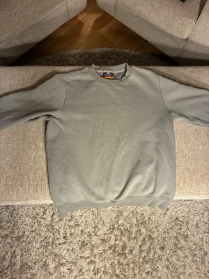 Grön crewneck sweatshirt Parajumpers - En stilren grön sweatshirt från Parajumpers med klassisk rund halsringning och ribbade muddar vid ärmslut och nederkant. Tröjan är enkel och passar perfekt till en avslappnad look. Tillverkad i mjukt material för extra komfort. Tröjan ser konstig ut på bilden men det är skuggan från lampan!