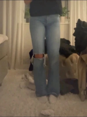 Ljusblå slitna bootcut jeans - Säljer ett par ljusblå bootcut jeans från g perfect jeans. Jeansen har en stor reva över ena knät för en trendig look och är tillverkade i klassisk denim. Perfekta för dig som gillar en avslappnad och cool stil.