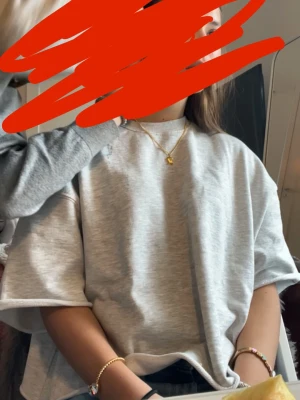 Ljusgrå oversized t-shirt - En enkel och stilren ljusgrå t-shirt i oversized modell. T-shirten har korta ärmar och rund halsringning. Tillverkad i mjukt bomullsmaterial som ger en avslappnad och trendig look. Perfekt att matcha med jeans eller shorts.