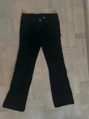 Svarta utsvängda manchesterbyxor - Snygga svarta lågmidjade manchesterbyxor med utsvängda ben och klassisk femficksmodell. Byxorna har knapp- och dragkedjestängning framtill och är tillverkade i mjuk manchester. 