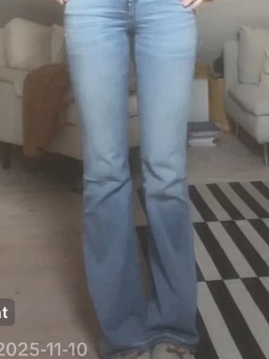 Ljusblå bootcut jeans - Säljer ett par ljusblå bootcut jeans med låg midja och klassisk femficksdesign. Jeansen har en snygg utsvängd passform från knät och ner, vilket ger en retrovibe. Perfekta för dig som gillar en avslappnad men trendig stil. Storlek 26/34 men jag har sprättat upp kanten så innerbensmåttet är 86 cm💕