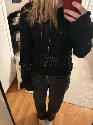 Svart stickad tröja från Tezenis - Säljer en svart stickad tröja från Tezenis med lång ärm och rund halsringning. Tröjan har ett genombrutet mönster och vågig kant nertill, vilket ger en snygg och trendig look. Perfekt att styla med jeans eller kjol.
