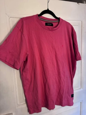 Röd t-shirt från Replay - Snygg röd t-shirt från Replay med klassisk rund halsringning och diskret logga på bröstet. T-shirten är enkel och stilren, perfekt för en avslappnad look. Tillverkad i mjuk bomull och har korta ärmar. Passar S/M.